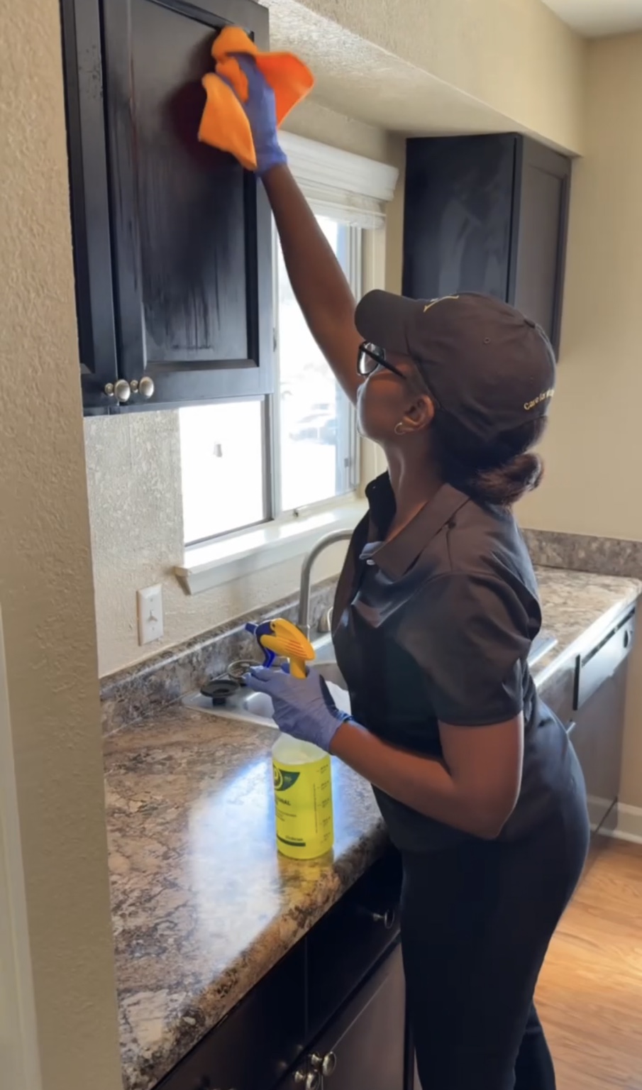 A Well Kept team member carefully cleaning kitchen cabinetry
